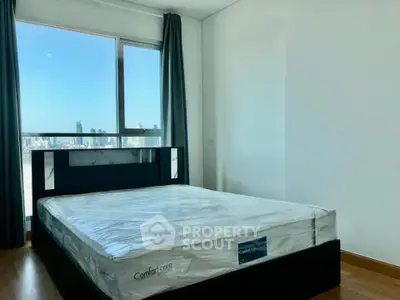 Spacious bedroom with city view and modern furnishings in high-rise apartment.