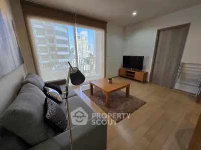 Modern living room with cozy sofa, wooden flooring, and large window offering city view.