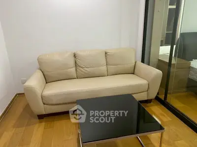 Modern living room with beige sofa and sleek black coffee table on wooden flooring.