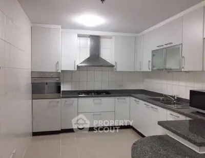Modern kitchen with sleek white cabinets and stainless steel appliances, featuring a gas stove and ample counter space.