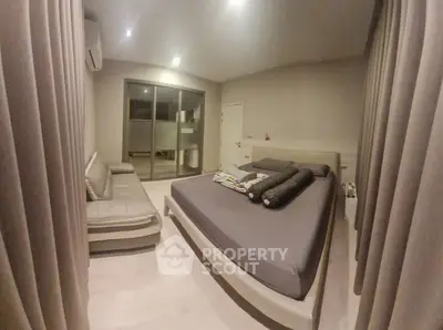 Spacious modern bedroom with cozy seating and large windows