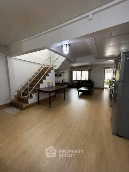 Spacious open-plan living room with modern staircase and wooden flooring
