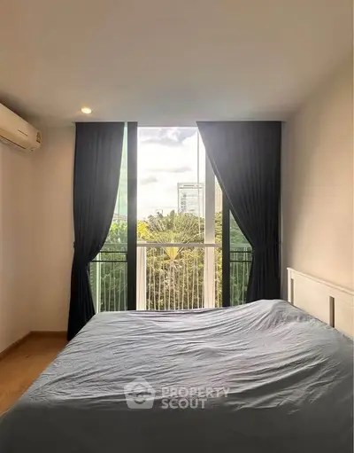 Bright bedroom with large window and scenic view, featuring modern decor and air conditioning.