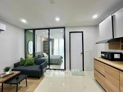 Modern open-plan living room with sleek kitchen and cozy bedroom view.