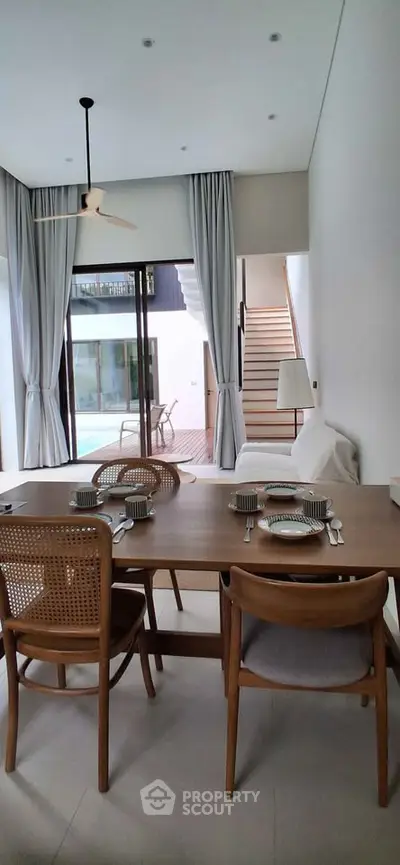 Modern dining area with wooden furniture and pool view in luxury home