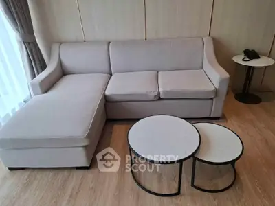 Modern living room with stylish beige sofa and nested coffee tables on wooden flooring.