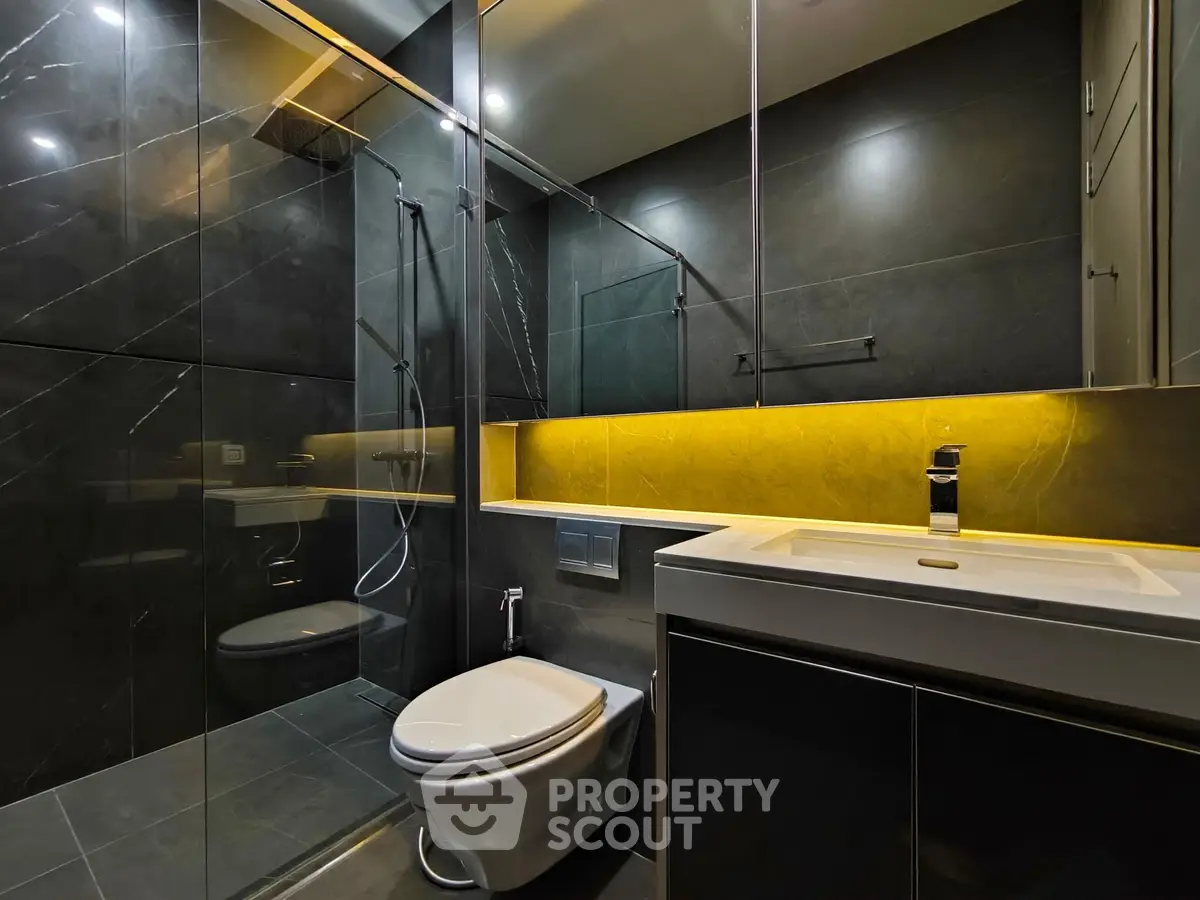 Luxurious modern bathroom with sleek black tiles and ambient lighting.