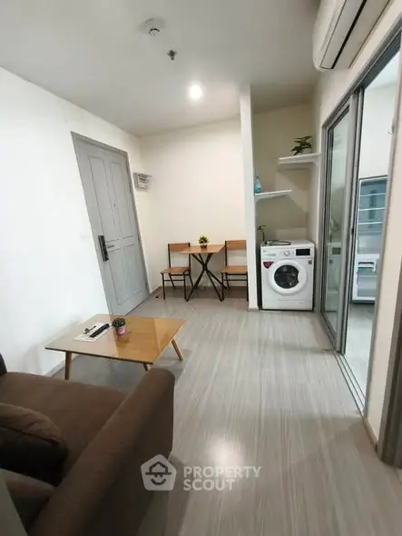 Modern living room with compact dining area and washing machine in cozy apartment.