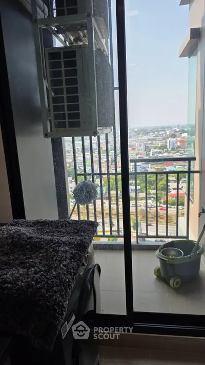 High-rise balcony with city view, featuring air conditioning unit and cleaning supplies.