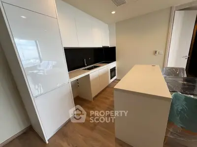 Modern kitchen with sleek white cabinetry and black backsplash in open layout.