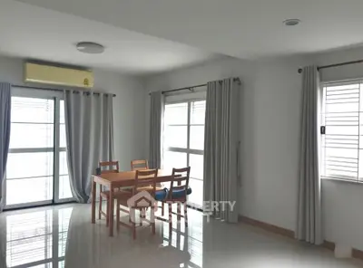 Bright dining area with large windows and modern furniture in a spacious apartment.
