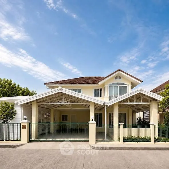 Charming two-story house with spacious driveway and elegant roof design under a clear blue sky.