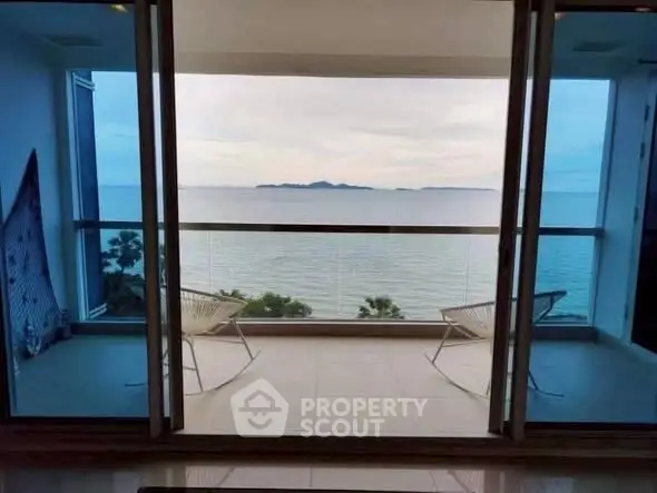Stunning ocean view from a modern balcony with sleek glass railing and cozy seating.