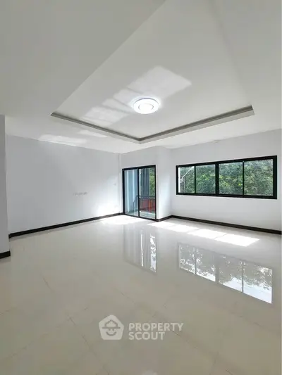 Spacious and bright living room with large windows and glossy tiled floor.