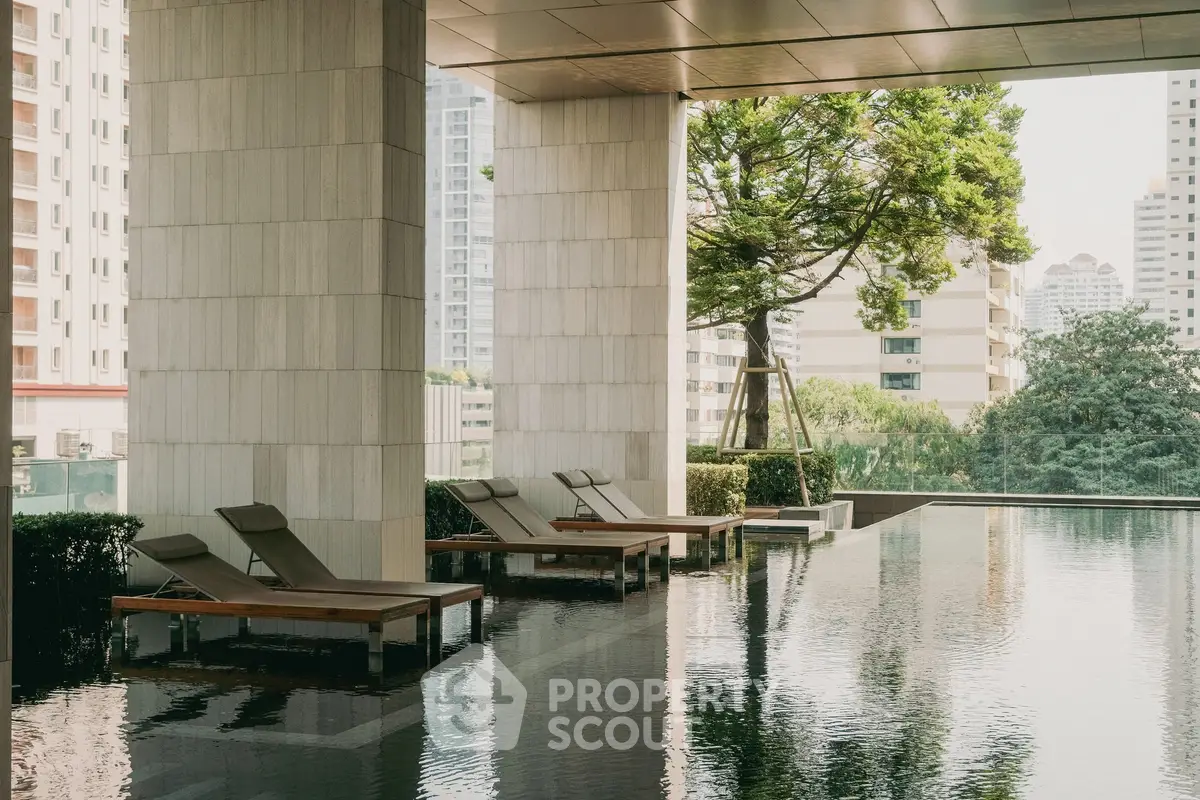 Luxurious poolside area with modern loungers and city view in a high-rise building.
