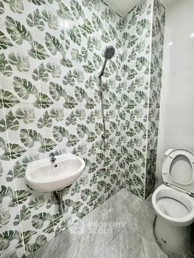 Modern bathroom with stylish leaf-patterned tiles and sleek fixtures.