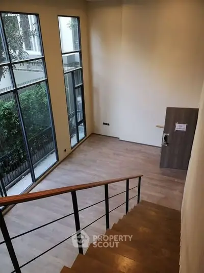 Spacious modern interior with high ceilings and large windows overlooking a garden.