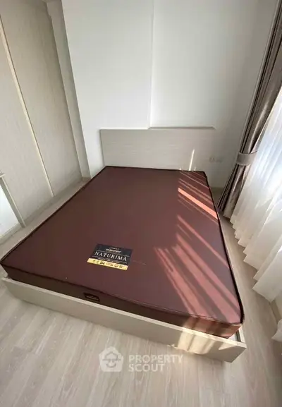 Cozy bedroom with natural light and modern furnishings, featuring a comfortable mattress and elegant curtains.