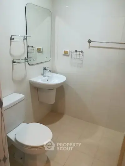 Modern bathroom with sleek fixtures and minimalist design, featuring a wall-mounted sink and toilet.
