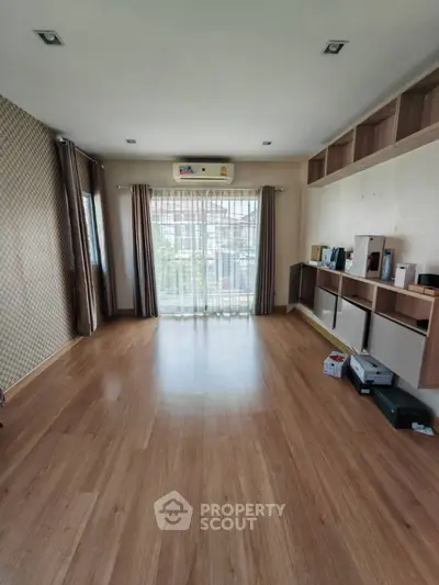 Spacious empty living room with wooden flooring and built-in shelves, perfect for customization.