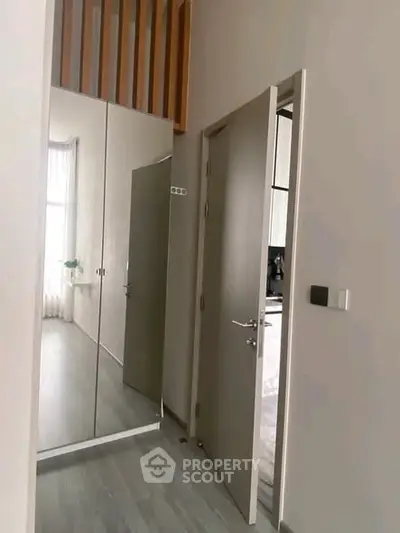 Modern interior hallway with mirrored closet doors and open kitchen view.