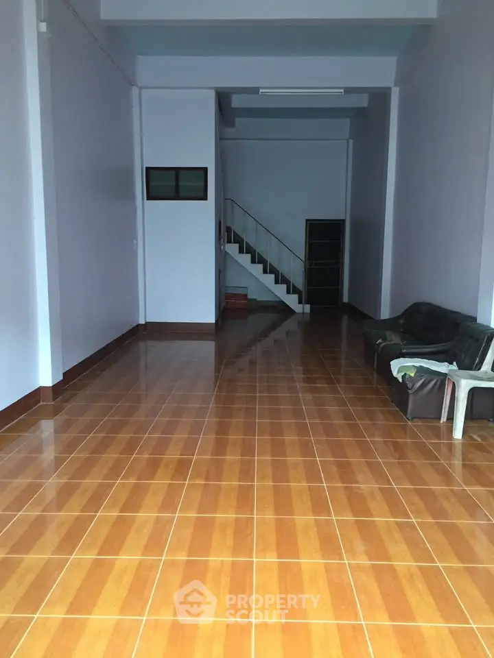 Spacious interior with tiled flooring and staircase, ideal for customization.