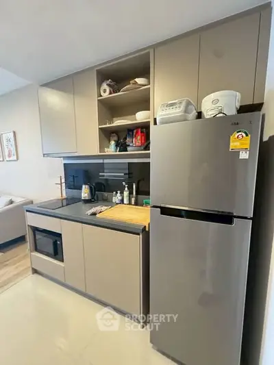 Modern kitchen with sleek cabinets and stainless steel fridge in stylish apartment.