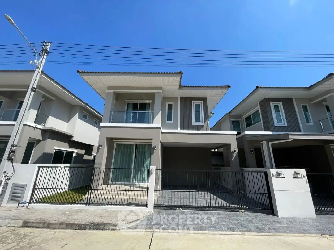 Modern two-story house with sleek design and spacious driveway under clear blue sky.