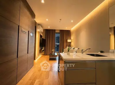 Modern living room with elegant lighting and open kitchen layout, featuring wooden flooring and sleek design.
