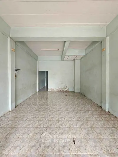 Spacious empty room with tiled flooring and pale green walls, ideal for customization.