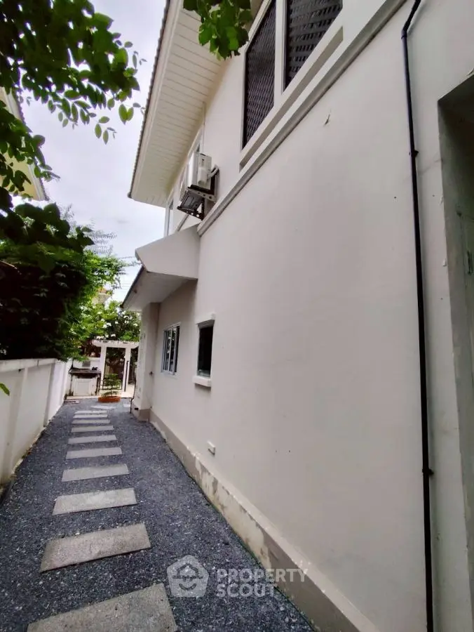 Charming exterior walkway of a modern home with lush greenery and sleek design.