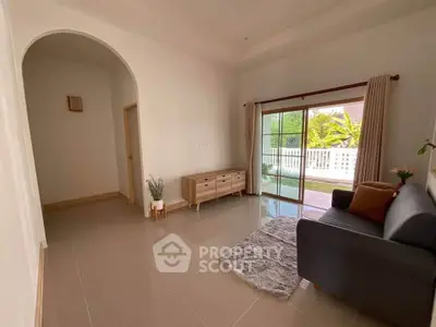 Spacious living room with modern decor and large sliding glass doors leading to a sunny balcony.