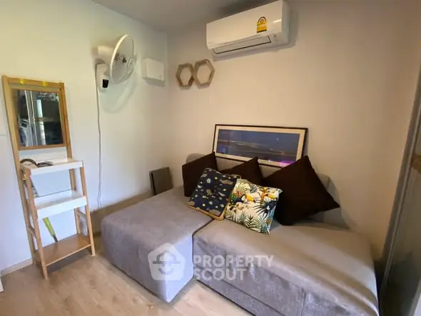 Cozy living room with modern sofa and air conditioning unit, perfect for relaxation.