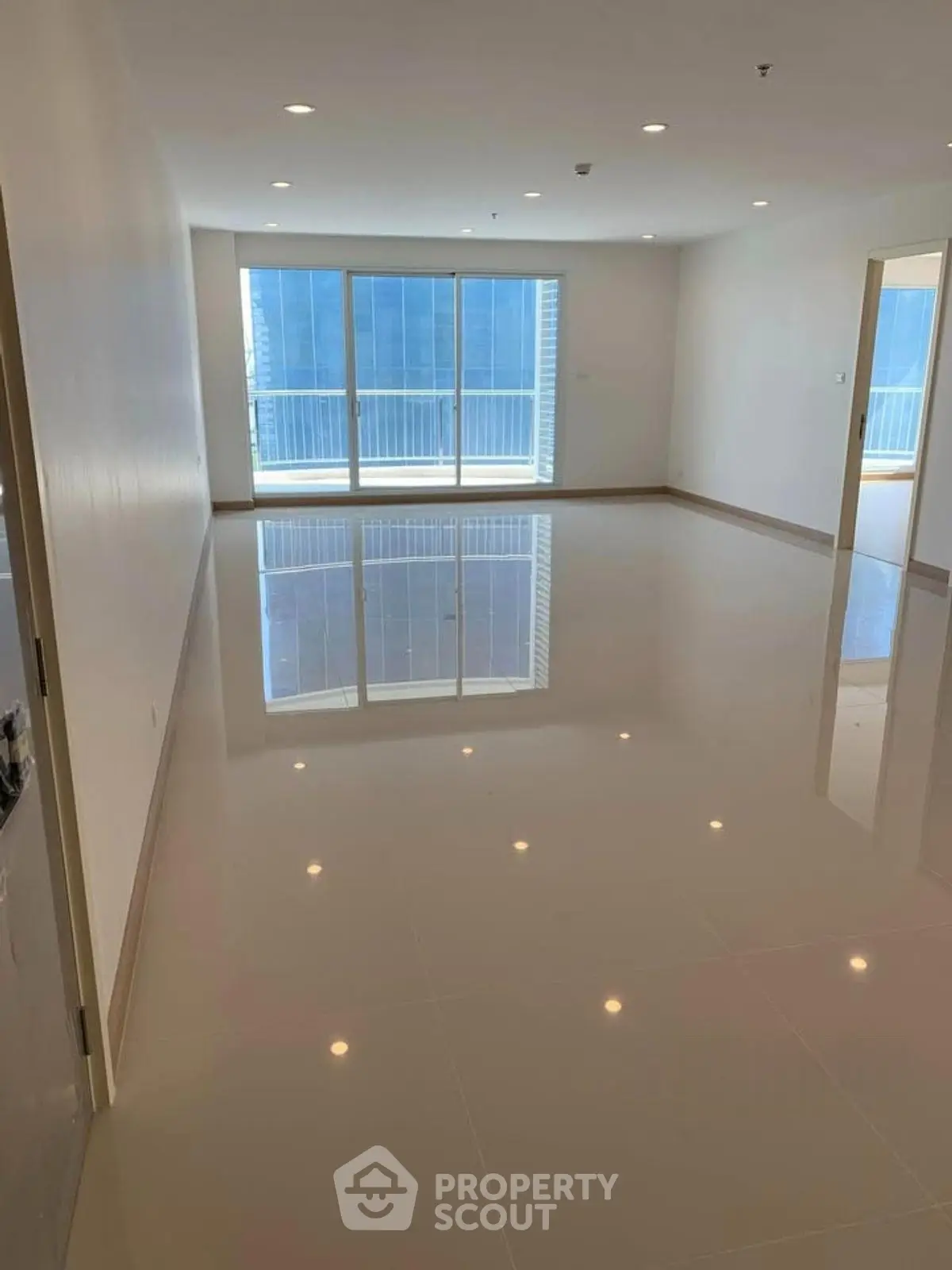 Spacious modern living room with glossy tiled floors and large windows offering ample natural light.