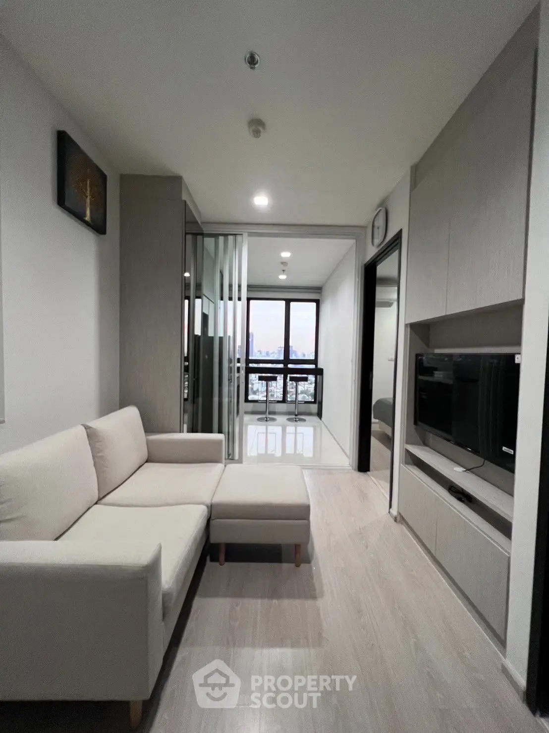 Modern living room with sleek design and city view, featuring a cozy sofa and built-in TV unit.