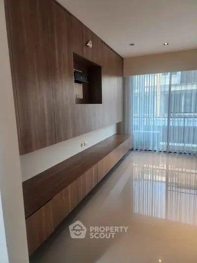Modern living room with sleek wooden cabinetry and large windows for natural light.