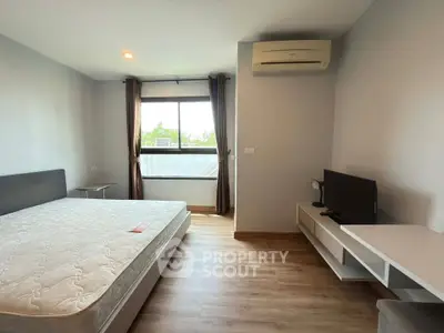 Spacious bedroom with modern furnishings and natural light, featuring a comfortable bed and sleek air conditioning unit.