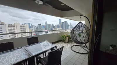 Stunning city view from a spacious balcony with modern outdoor furniture and hanging chair.