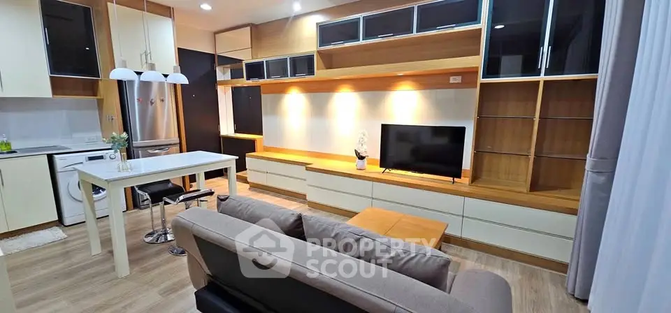 Modern living room with open kitchen, featuring sleek cabinetry and cozy seating area.