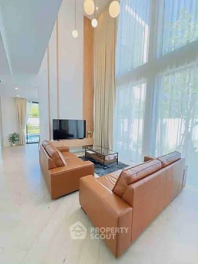 Luxurious high-ceiling living room with modern leather sofas and large windows