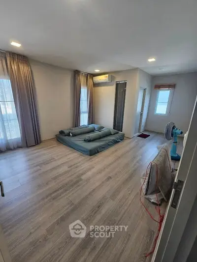 Spacious bedroom with minimalist decor and large windows for natural light.