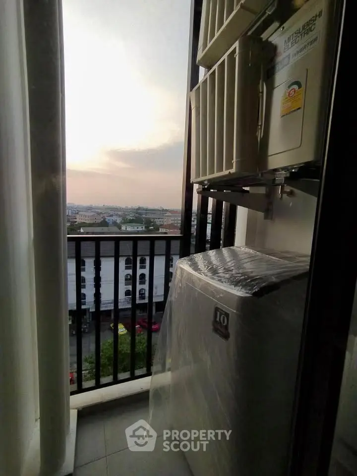 Compact balcony with city view and washing machine setup at sunset.
