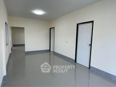 Spacious empty room with tiled flooring and multiple doors, ideal for customization.