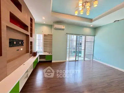 Spacious living room with modern lighting and large windows opening to a balcony.