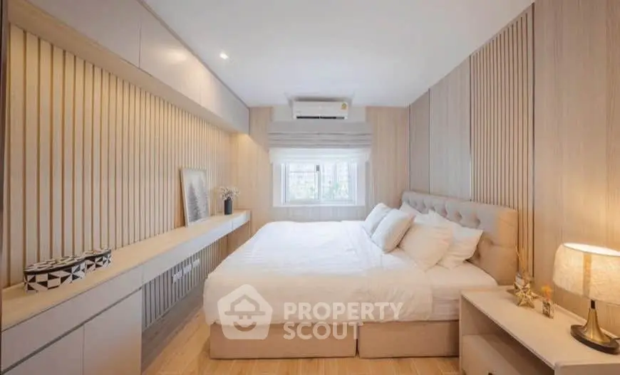 Elegant bedroom with modern decor and natural light, featuring a cozy bed and stylish wooden accents.
