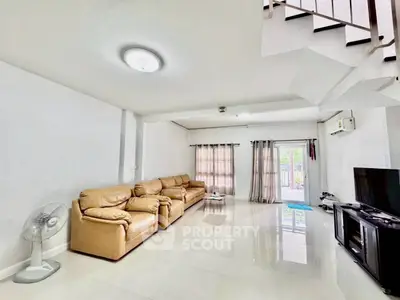 Spacious living room with leather sofas and modern decor in a bright, airy home.