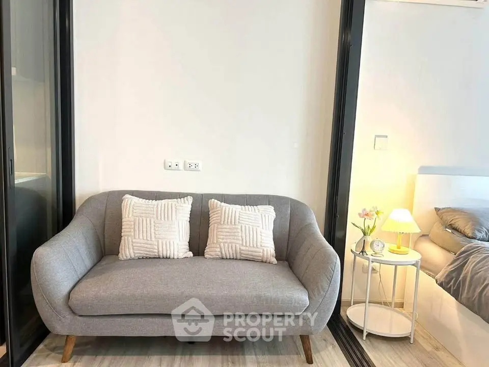 Modern living room with stylish gray sofa and cozy bedroom view