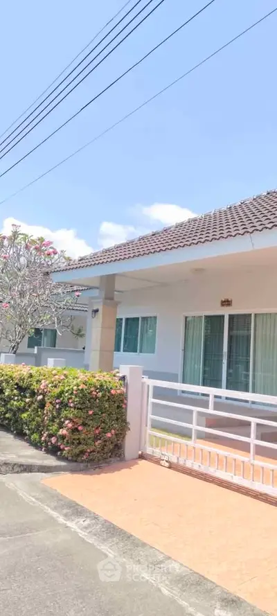 Charming single-story home with tiled roof and lush garden in serene neighborhood.