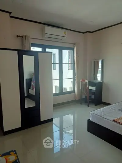 Spacious bedroom with modern furniture and large window for natural light.