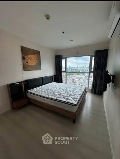 Spacious bedroom with city view, featuring a large window and modern furnishings, perfect for urban living.
